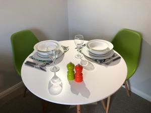 a white table with green chairs and plates and wine glasses at Coast Apartment in Sidmouth