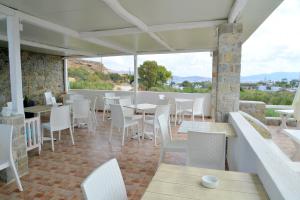 a restaurant with white chairs and tables and windows at Hotel Glaronissia Rooms & Suites in Pollonia