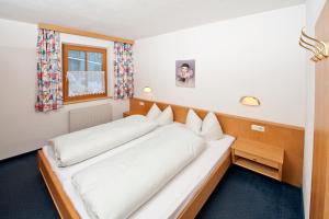 ein großes weißes Bett in einem Zimmer mit Fenster in der Unterkunft Landhaus Schiestl in Fulpmes