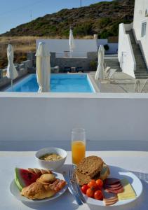 a table with a plate of food and a glass of orange juice at Hotel Glaronissia Rooms & Suites in Pollonia
