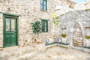 a stone house with a green door and a potted tree at Two Stone Homes Asteria in Marmaris