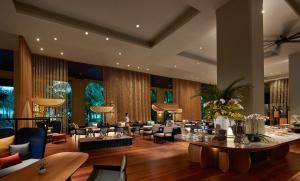 a lobby of a hotel with tables and chairs at PARKROYAL Penang Resort in Batu Ferringhi