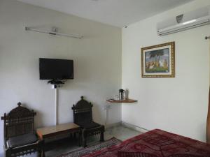 een kamer met 2 stoelen en een televisie aan de muur bij Rising Sun Retreat in Mount Ābu