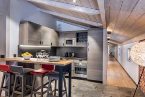a kitchen with wooden ceilings and a wooden island with bar stools at Chalet Skadi - Village Montana in Val dʼIsère