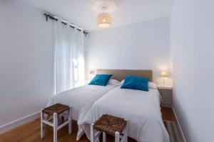 two beds in a white room with blue pillows at Apartamento Carlos V in Hondarribia
