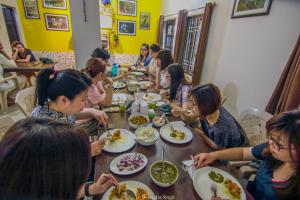 a group of people sitting around a table eating food at Iora Guest House in Bharatpur