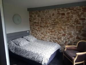 1 dormitorio con cama y pared de piedra en Le Tempo, en Entrecasteaux