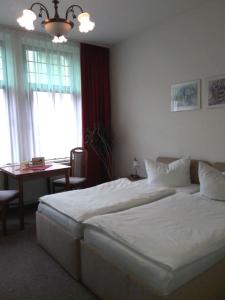 a bedroom with a large white bed and a table at Pension Zum Burschen in Eisenach