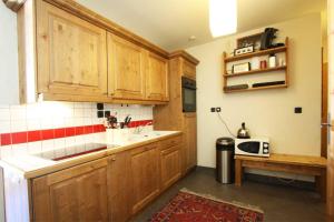 uma cozinha com armários de madeira e um micro-ondas em Le Paradis ski apartment - Chamonix All Year em Chamonix-Mont-Blanc