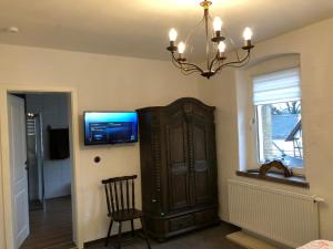a room with a chandelier and a cabinet with a television at Pension Alex in Brahmenau