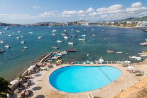 a swimming pool next to a body of water with boats at Hotel Simbad Ibiza in Talamanca