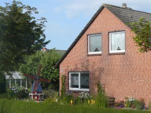 uma casa de tijolos vermelhos com duas janelas e um jardim em Haus Magnussen em Dagebüll
