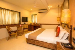 ムンバイにあるAccord Hotelのベッドとデスクが備わるホテルルームです。