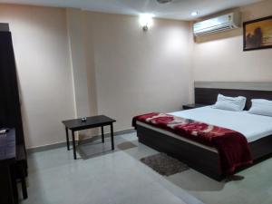 迪布鲁加尔Hotel Raj Palace的一间卧室配有一张床和一张小桌子