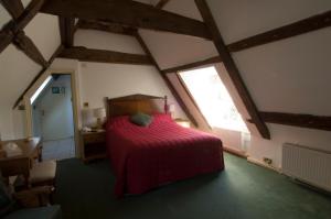 a bedroom with a red bed in a attic at Stower Grange Hotel in Norwich
