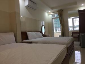 a hotel room with two beds and a window at DUY HUY hotel & apartment in Nha Trang