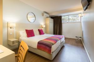 a bedroom with a bed and a table and a mirror at Hotel Londres Estoril / Cascais in Estoril