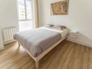 パリにあるWelkeys - Bonne Nouvelle Apartmentのウッドフロアの白いベッドルームのベッド1台