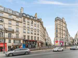 una calle con coches estacionados frente a los edificios en Welkeys - Bonne Nouvelle Apartment en París