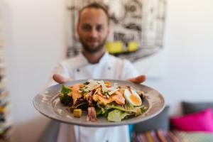 a man holding a plate of food on a table at Hotel Londres Estoril / Cascais in Estoril