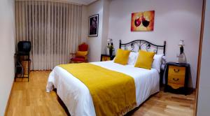 a bedroom with a large bed with a yellow blanket at CLAREN'S GUESTHOUSE in Cangas del Narcea