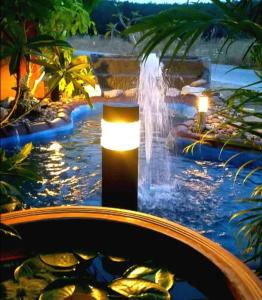 a waterfall in a pond with a fountain at Somjainuk Resort 2 in Pluak Daeng