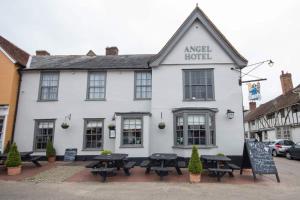 a white building with picnic tables in front of it at The Angel Hotel in Lavenham