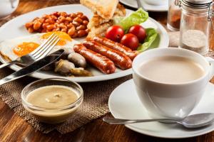 un tavolo con un piatto di prodotti per la colazione e una tazza di caffè di Green Palace Hotel a Yerevan