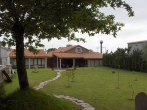 ein Haus mit einem Garten mit einem Baum in der Unterkunft Casa Rural Dona María in Ordes