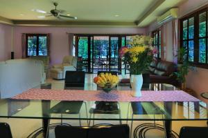 Coral Beach Pool Villa Khao Lak - SHA Extra Plus في خاو لاك: غرفة معيشة مع طاولة زجاجية عليها زهور