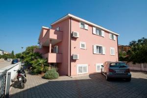 a pink building with a car parked next to it at Apartments Maric with parking in Umag