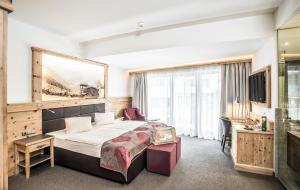 a hotel room with a bed and a desk at Hotel Elisabeth, 4 Sterne Superior in Kirchberg in Tirol