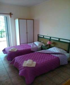 2 Betten in einem Zimmer mit lila Decken in der Unterkunft Maviria in Monemvasia