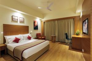 a hotel room with a large bed and a desk at Ramee Panchshil in Kolhapur