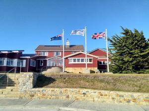 una casa roja con tres banderas delante de ella en Malvina House Hotel, en Stanley