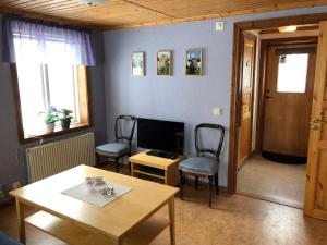 Moheda的住宿－Vegby Bolsgård "Lillstugan"，客厅配有桌椅和电视。