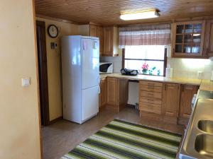 a kitchen with a white refrigerator and wooden cabinets at Vegby Bolsgård "Lillstugan" in Moheda +11 photos