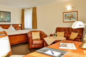 a hotel room with a bed and leather furniture at Waldhotel Rheinbach in Rheinbach