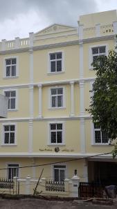 a large yellow building with white columns and windows at Vazeer Residancy in Hyderabad