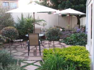 un patio con mesas, sillas y una sombrilla en Melody Guest House, en Centurion