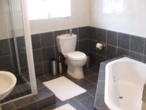a bathroom with a toilet and a tub and a sink at Melody Guest House in Centurion