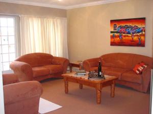 een woonkamer met 2 banken en een salontafel bij Melody Guest House in Centurion