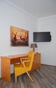 einen Schreibtisch mit einem gelben Stuhl und ein Gemälde an der Wand in der Unterkunft Pension zum Strell in Hollabrunn
