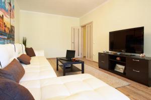 a living room with a white couch and a flat screen tv at PaulMarie Apartments on Mazurova in Gomel