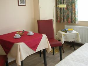 um quarto com uma mesa e duas cadeiras e uma mesa com um pano vermelho em Liry's Home em Tongeren