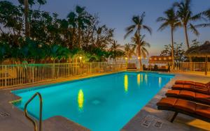 a pool with chairs and palm trees at night at Atlantic Bay Resort in Key Largo