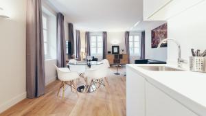 a white kitchen with a table and white chairs at T3 luxe hyper centre in Bordeaux