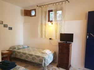 een kleine slaapkamer met een bed en een televisie bij Con i piedi nell'acqua in Stromboli