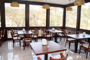 a restaurant with tables and chairs and large windows at Hotel Miraj in Râmnicu Vâlcea