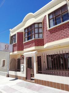 un edificio de ladrillo rojo con ventanas de barrica negra en Hotel Aguilar, en Uyuni